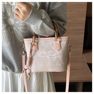 Detail of embroidered landscape bucket bag with bamboo handle and pearl tassel charm