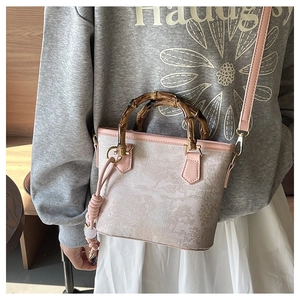 Detail of pink embroidered bucket bag with natural bamboo handle and landscape pattern
