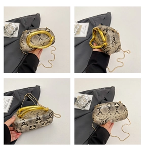 Detail of snake print clutch box bag featuring gold ring handle and metal chain strap
