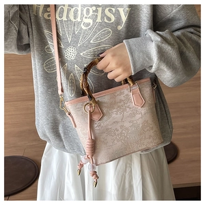 Detail of bamboo handle and toile de jouy print on a crossbody bucket bag