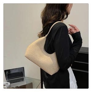 Detail of oat beige half-moon underarm bag with woven texture worn by model in office