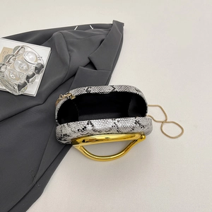 Close-up of snake skin acrylic clutch with golden metal handle and interior lining detail