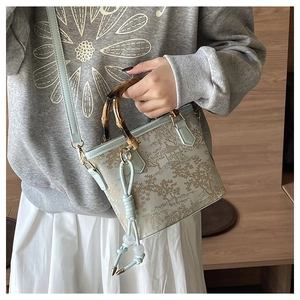 Detailed view of bucket bag with bamboo handle and traditional landscape print
