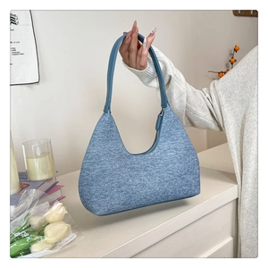 Detail shot of a blue denim hobo bag with zip closure in a minimalist lifestyle setting