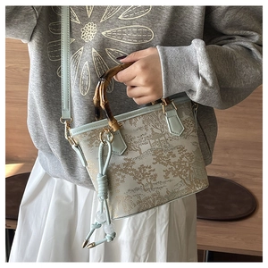 Detail of embroidered landscape bucket bag with natural bamboo handle and beaded tassel