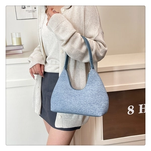 Detailed texture of blue woolen underarm bag shown in a cozy indoor lifestyle setting