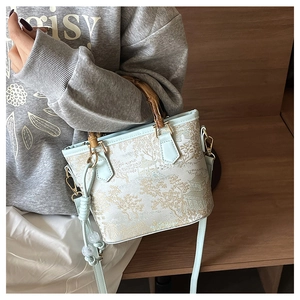 Detail of mint green embroidered bucket bag with bamboo handle and traditional scenery