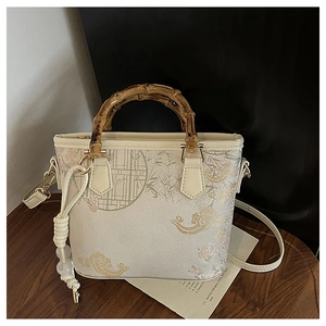 Detail of jacquard bucket bag with natural bamboo handle and pearl tassel ornament