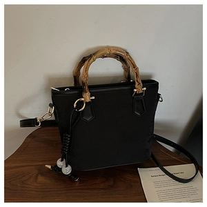 Detail of vintage black leather bucket bag with classic bamboo handle and bead tassel