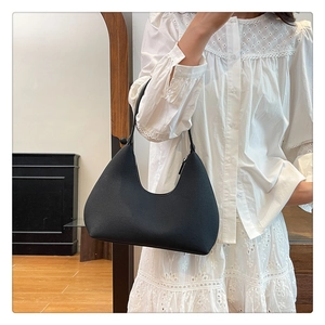 Detail of black semi-circle Hobo bag with textured faux leather finish on a shoulder
