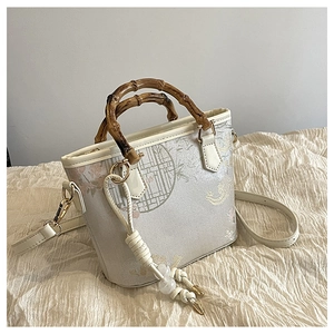 Detailed close-up of oriental floral embroidery and natural bamboo handle on bucket bag