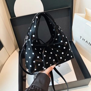 Sac à main à pois noir et blanc avec nœud et pendentif argenté sur boîte cadeau