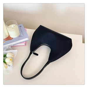 Close-up of a minimalist black crescent shoulder bag with smooth zipper and textile texture