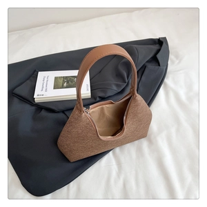 Close-up detail of the brown felt texture and smooth leather shoulder strap on the handbag