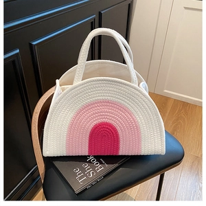 Detail of a handmade semi-circular woven cotton bag with a pink rainbow gradient design