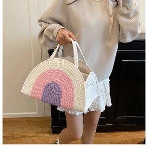 Detailed view of rainbow striped woven bag carried by a model in a cozy interior setting