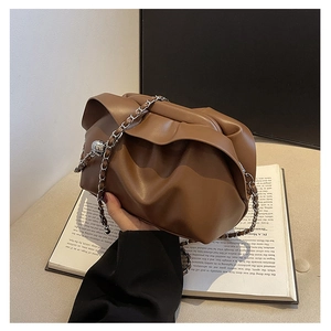 Detail of brown pleated cloud bag featuring a silver metal chain strap and spherical hardware