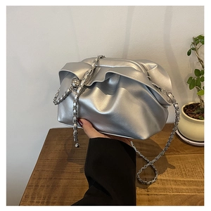 Close-up of silver pleated cloud bag with metal chain strap and spherical charm