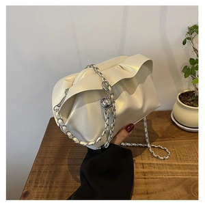 Close-up of cream cloud bag featuring ruched texture and silver metal chain strap detail