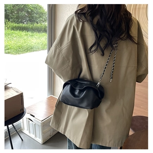 Detail of minimalist black pleated cloud bag with elegant silver metal chain strap