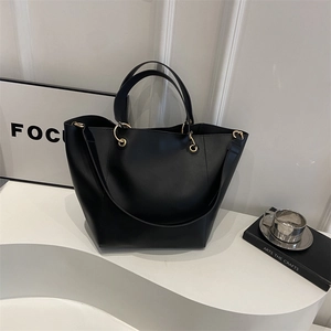 Sac seau noir minimaliste avec anneaux dorés et doubles poignées sur fond blanc épuré