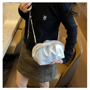 Detail of white pleated cloud bag with silver chunky chain strap on a model shoulder