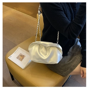 Detailed shot of an ivory cloud bag with silver chain strap worn over the shoulder