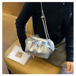Detail of silver metallic cloud bag with ruffled pleats and fine chain strap on a model