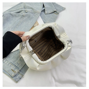 Detail view showing brown striped fabric lining and interior zipper pocket of a white clutch