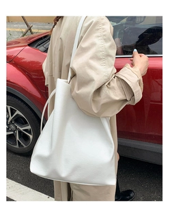 Detailed view of a white soft leather tote bag worn with a khaki coat in a street style
