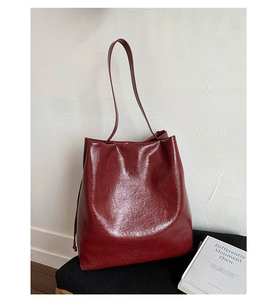 Close-up of vintage oil wax texture on large burgundy tote bag with shoulder strap