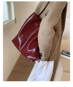 Detail of dark burgundy oil wax leather tote bag worn with a chic beige blazer