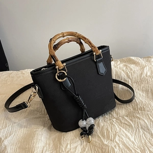 Classic black bucket bag with natural bamboo handle and decorative marble bead tassel
