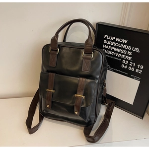 Détail du sac à dos vintage en similicuir noir avec sangles brunes et boucles en bronze