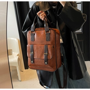 Détail du sac à dos vintage en cuir marron avec sangles à boucle porté par un mannequin