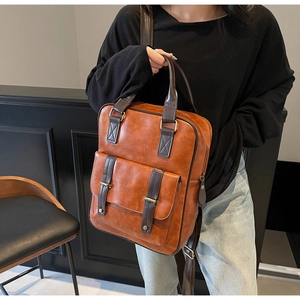 Détail du sac à dos rétro en cuir caramel avec poche avant à boucles et finitions bronze