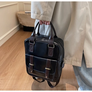Détail d'un sac à dos rétro en cuir brillant noir avec des contrastes de marron