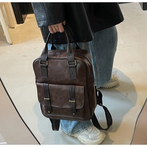 Vue détaillée d'un sac à dos rétro en cuir marron foncé avec boucles et poignée haute