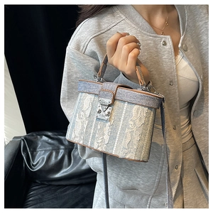 Detail of blue denim and lace bucket bag with leather handle and silver metal buckle