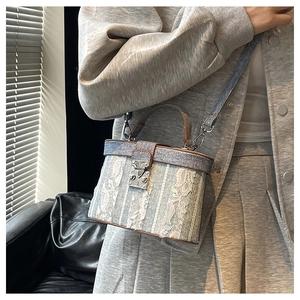 Dettaglio borsa a secchiello in denim blu chiaro con pizzo floreale e pelle marrone