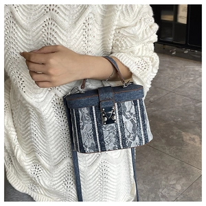 Dettaglio della borsa a tracolla in denim blu e pizzo bianco con fibbia in argento