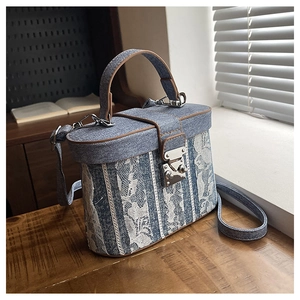 Dettaglio borsa vintage in denim con motivi in pizzo floreale e finiture in pelle marrone