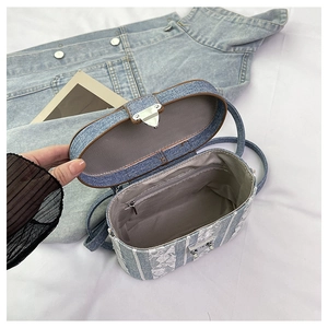 Detail of denim crossbody bag interior showing main compartment and zipper pocket