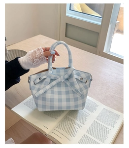 Vue détaillée du sac à main à carreaux bleu clair avec grand nœud sur un magazine