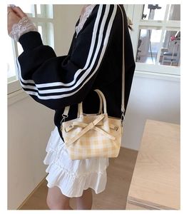 Détail du motif à carreaux jaunes et nœud en tissu sur un petit sac seau avec sangle