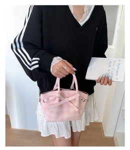 Modèle portant un sac seau à carreaux roses avec nœud décoratif et détails argentés