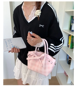 Détail du sac seau à carreaux roses avec un grand nœud décoratif et des anneaux en D en métal