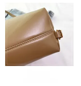 Close-up of khaki leather stitching and golden hardware square buckle on the backpack