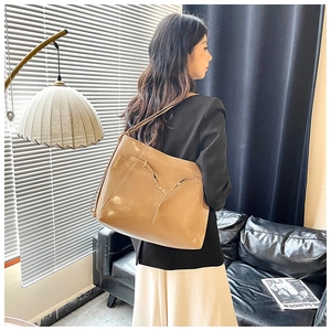 Side view of a large khaki tote bag styled as a minimalist leather backpack on model