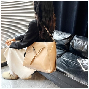Detail of glossy beige tote bag featuring decorative strap buckle and premium leather finish